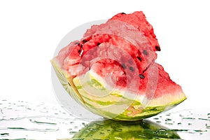 Watermelon big piece with cracks and water drops on white mirror background with reflection isolated close up