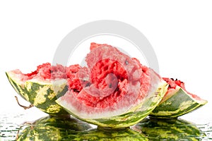 Watermelon big pieces with cracks and water drops on white mirror background with reflection isolated close up