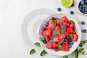 Watermelon and blueberry fruit salad with mint and lime juice in a plate on white background. Top view with copy space