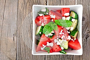 Watermelon, cucumber and feta cheese salad on a wood background