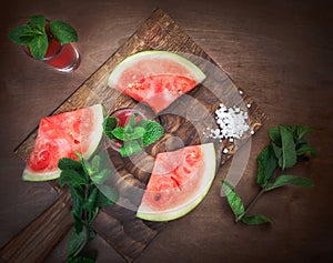 Watermelon drink watermelon pieces in a rustic wooden background.