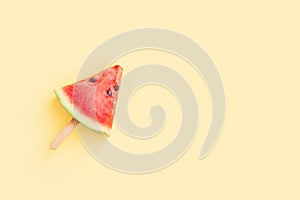 Watermelon fruit sliced with wood ice cream stick on yellow background