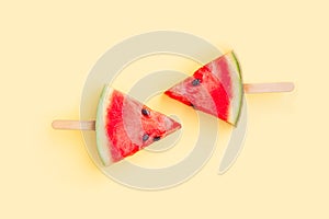 Watermelon fruit sliced with wood ice cream stick on yellow background