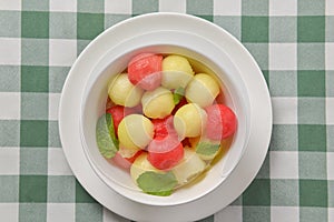 Watermelon granita ice cream. Melon and watermelon sorbet ice cream balls in a white bowl over green plaid table cloth