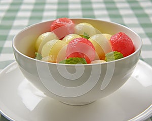 Watermelon granita ice cream. Melon and watermelon sorbet ice cream balls in a white bowl over green plaid table cloth