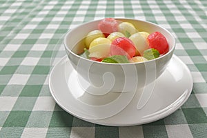 Watermelon granita ice cream. Melon and watermelon sorbet ice cream balls in a white bowl over green plaid table cloth.