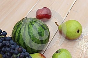 Watermelon, grapes, pear and apple on the background of the boards.