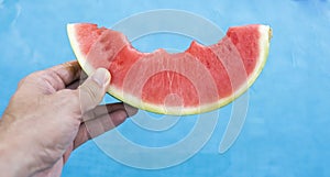 Watermelon in the hand of a girl in swimming pool