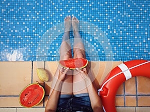 Watermelon in hands of young girl, sitting near the swimingpool