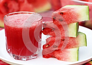 Watermelon juice with sliced fruit on white plate