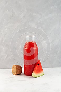 Watermelon juice or smoothie in glass bottle. Refreshing drink with fresh watermelon juice. Agua fresca cocktail. Grey background