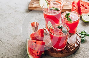 Watermelon lemonade with lime and fresh basil leaves on concrete background. Refreshing summer drink