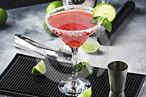 Watermelon margarita, alcoholic cocktail with silver tequila, lime juice, mint, watermelon and crushed ice, metal bar tools, gray photo