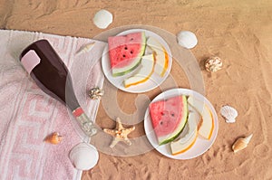 Watermelon, melon, bottle of champagne, starfishes and seashells on sand beach. Top view