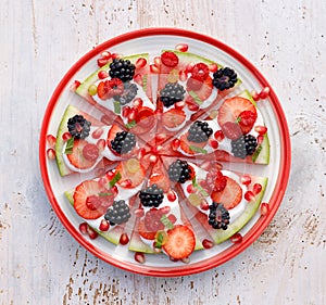 Watermelon pizza, vegetarian, fruit  pizza with creamy natural yogurt and fresh fruits  on a plate, on a white wooden table, top v