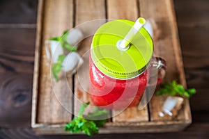 Watermelon refreshing smoothie in a jar close-up and copy space. Watermelon smoothie with a heart of watermelon, mint, ice on a te