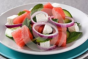 Watermelon salad with feta cheese,mint,onion and cucumber on gray background.