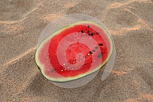 A watermelon on the sandy beach on the sunset.