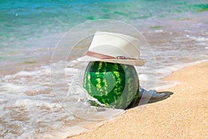 Watermelon by the sea in a salt hat on the beach. Creative concept of summer, travel, vacation, tourism, vacations