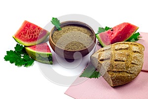 Watermelon seeds flour on ceramic bowl, watermelon slices and homemade bread isolated on white background