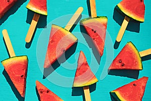 Watermelon slice popsicles on blue wood background.