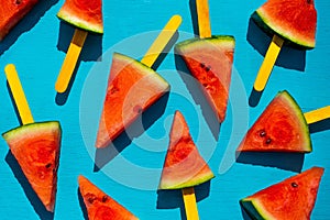 Watermelon slice popsicles on blue wood background.