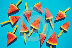 Watermelon slice popsicles on blue wood background.