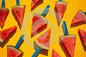 Watermelon slice popsicles on yellow wood background.