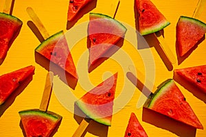Watermelon slice popsicles on yellow wood background.