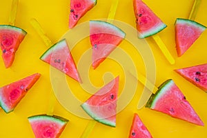 Watermelon slice popsicles on yellow wood background.