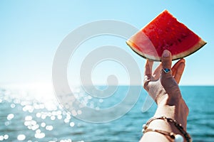 Watermelon slice in woman hand over sea