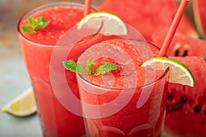 Watermelon slushie with lime, summer refreshing drink in tall glasses on a blue rusty background