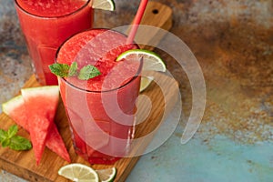 Watermelon slushie with lime, summer refreshing drink in tall glasses on a blue rusty background. with copy space