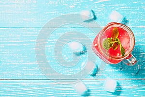 Watermelon smoothie in jar with fresh watermelon slices on blue background top view