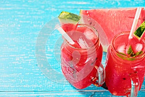 Watermelon summer cocktail with ice and mint leaves. Cold refreshment drink on blue wooden background with copy space.