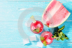 Watermelon summer cocktail with ice and mint leaves. Cold refreshment drink on blue wooden background with copy space.