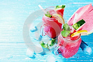 Watermelon summer cocktail with ice and mint leaves. Cold refreshment drink on blue wooden background with copy space.