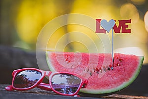 Watermelon and sunglasses on table outdoors