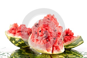 Watermelon three big pieces with cracks and water drops on white mirror background with reflection isolated close up