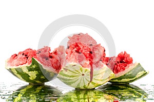 Watermelon big pieces with cracks and water drops on white mirror background with reflection isolated close up