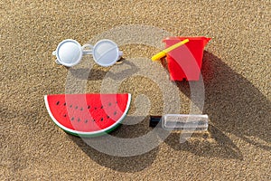 Watermelon toy with sunglasses on a sand background. Minimal summer vacation concept