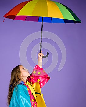 Waterproof accessories for children. Kid girl happy hold colorful umbrella wear waterproof cloak. Enjoy rainy weather