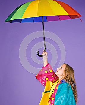 Waterproof accessories for children. Kid girl happy hold colorful umbrella wear waterproof cloak. Enjoy rainy weather