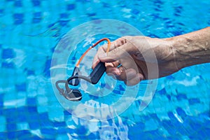 Waterproof audio device submerged in water. Headphones with bone conduction technology. Male hand submerged in water