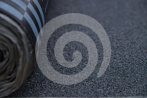 Waterproof bitumen roll covered with insulation materials, abstract background, closeup texture.