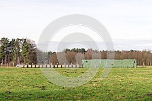 A waterproof covered stack of hay bales standing in a field