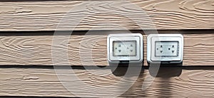 Waterproof electrical sockets installed outdoors on dark wooden walls