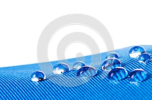 Waterproof fabric with waterdrops close up, on white background