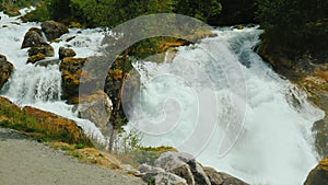Waters of the waterfall, at the bottom of the bridge in the distance. Meltwater from the glaciers in the mountains, the