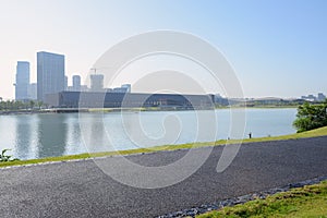 Waterside blacktopped path in summer morning with modern buildings across lake photo